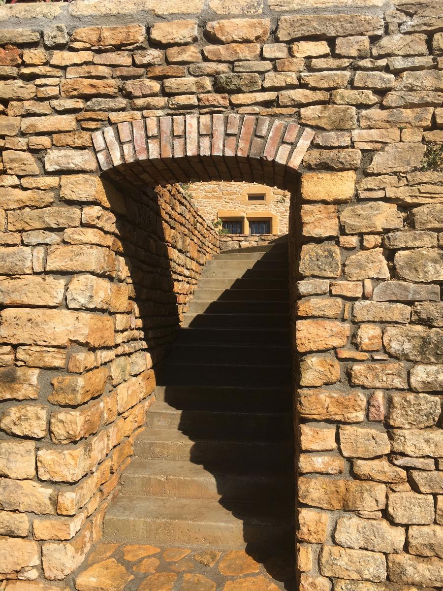 Vue du linteau en brique et de l'ancien mur en pierre dorée dans lequel vient s'insérer l'escalier